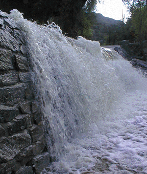 This is a photograph of flood waters flowing furiously over the first bridge.